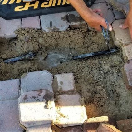 MASONRY! A mason laying paver stones to create a walkway in the backyard landscape.